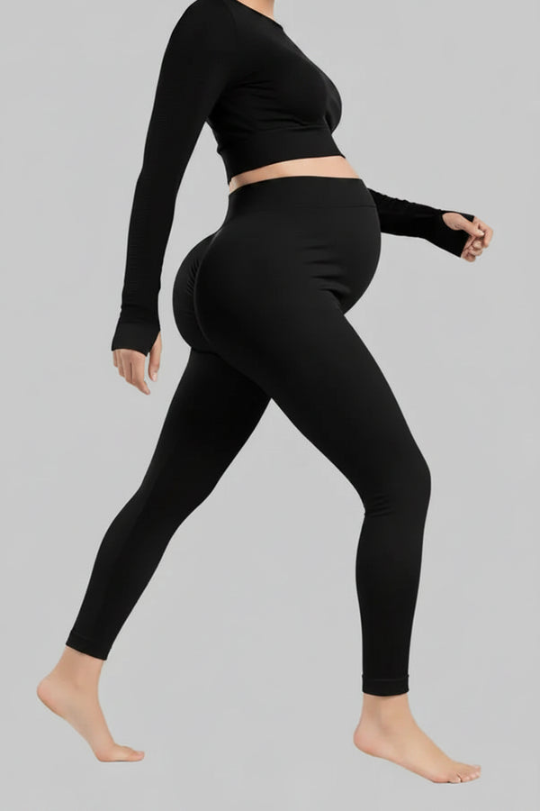 Person wearing black leggings and a black long-sleeve top on a gray background