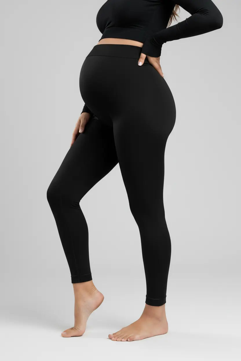 Person wearing black leggings and a black top on a plain background