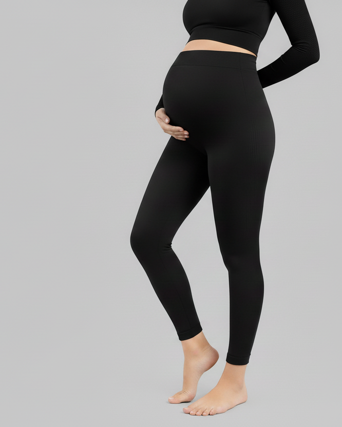 Person wearing black leggings and a black top on a gray background