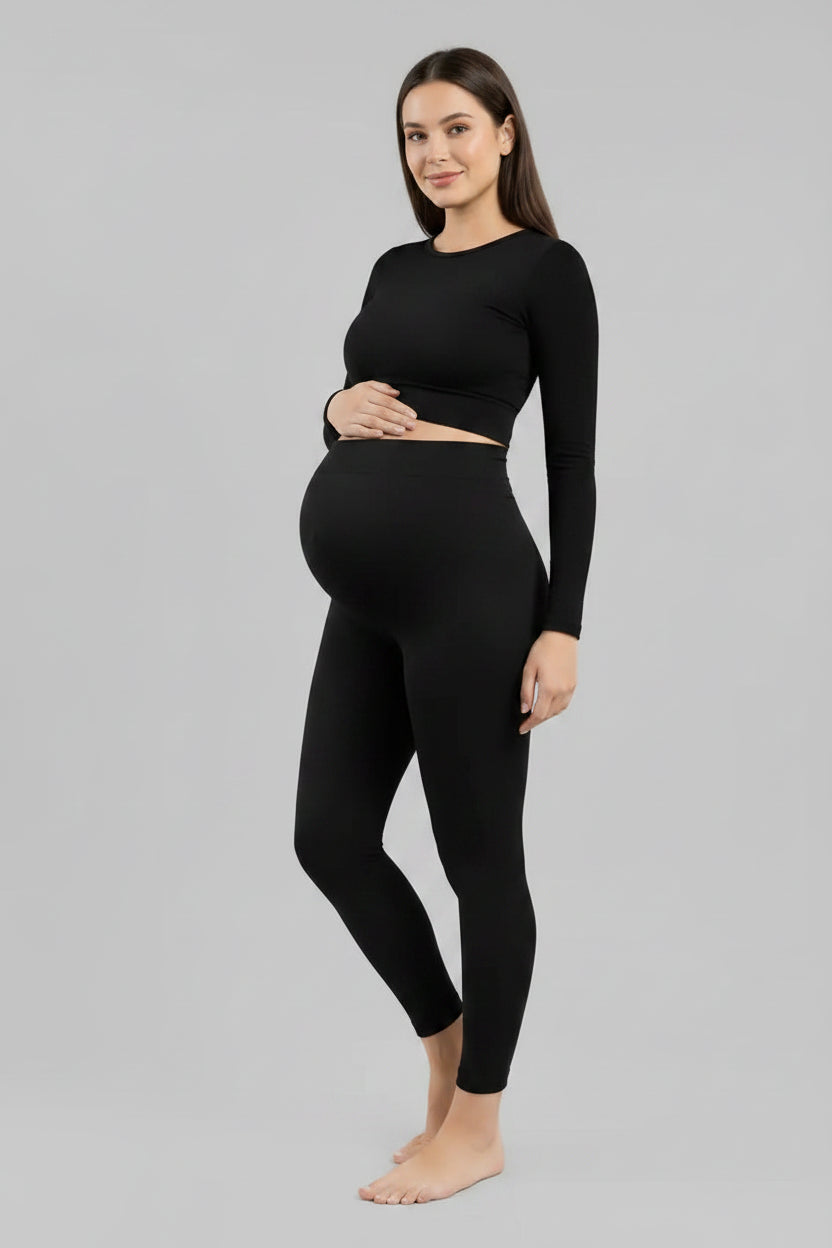 Person wearing black leggings and a matching top on a gray background