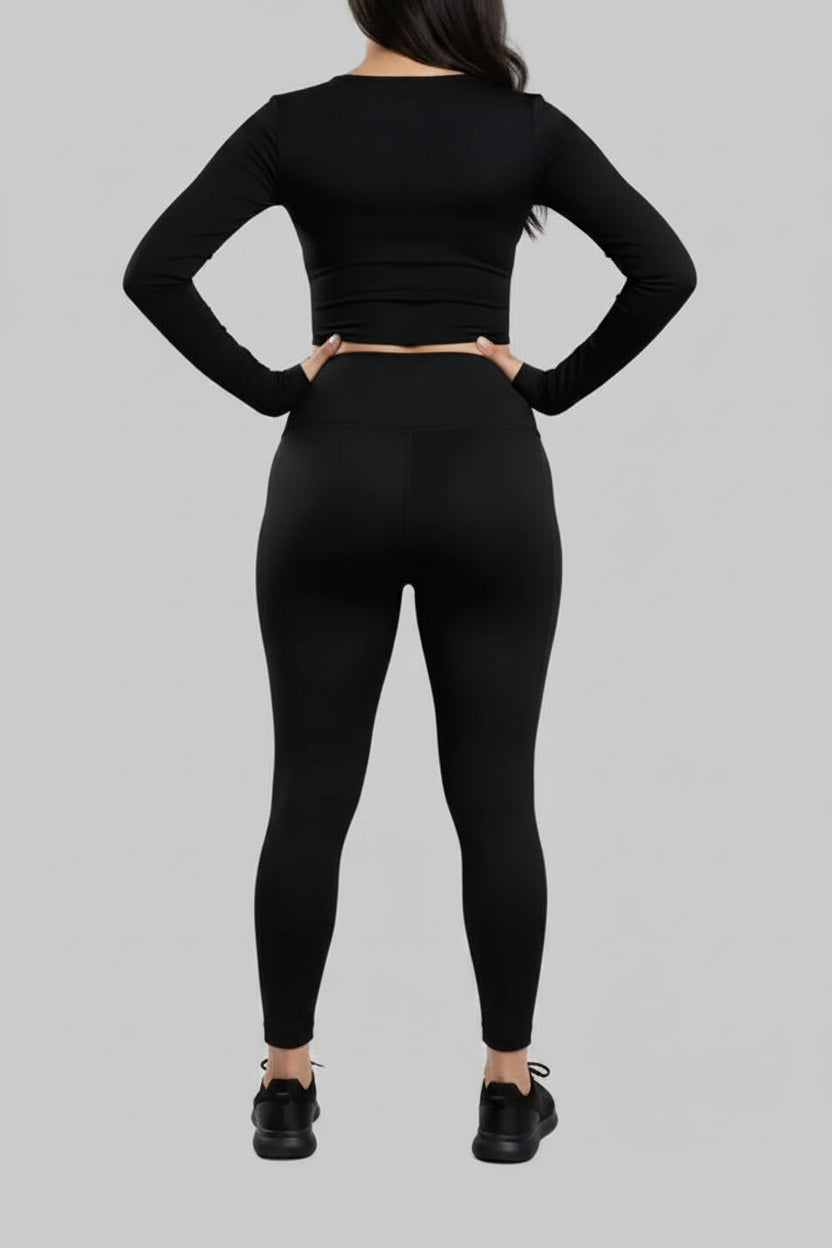 Person wearing a black long-sleeve top and leggings on a gray background