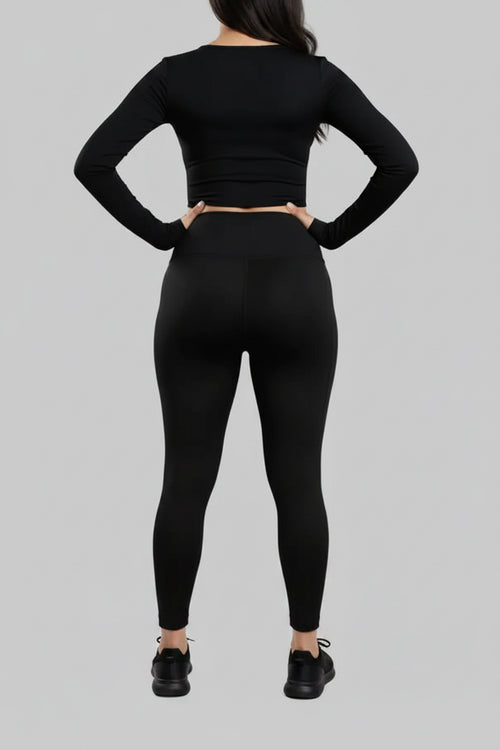Person wearing a black long-sleeve top and leggings on a gray background