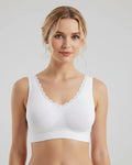Woman wearing a white bralette against a plain background