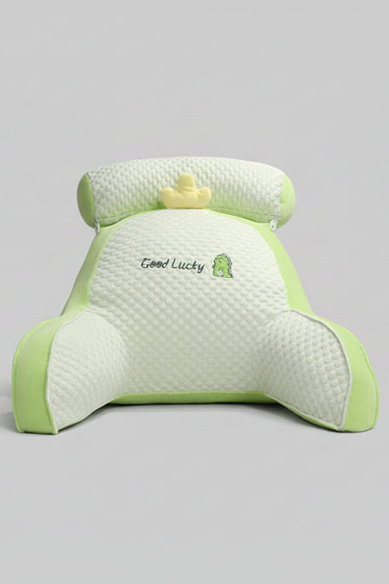 Green and white pillow with 'Good Lucky' embroidery on a bed