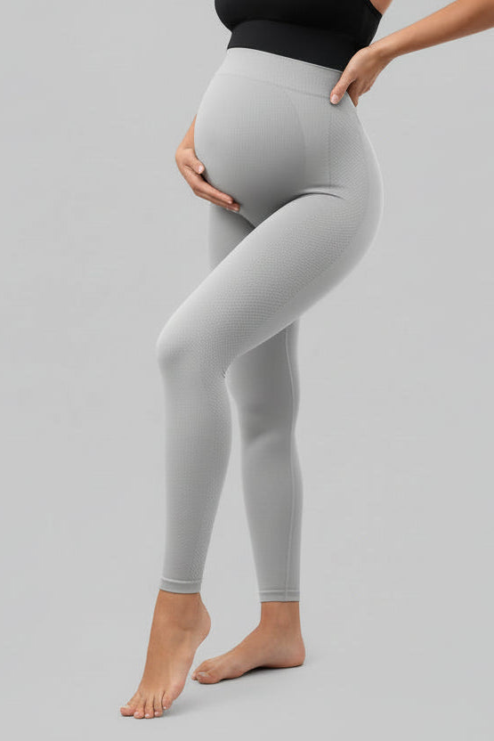 Person wearing beige leggings sitting on a couch in a living room.