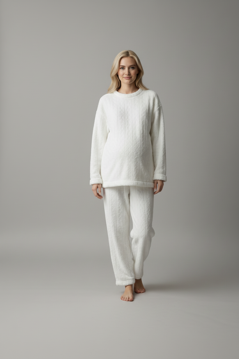 Woman wearing a white outfit standing against a plain background