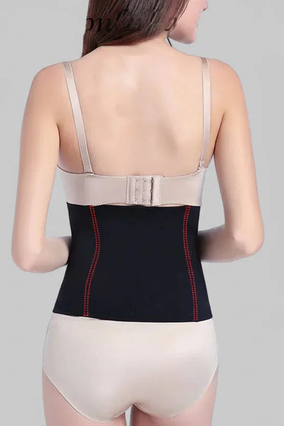 Woman wearing a black compression garment with red accents on a gray background