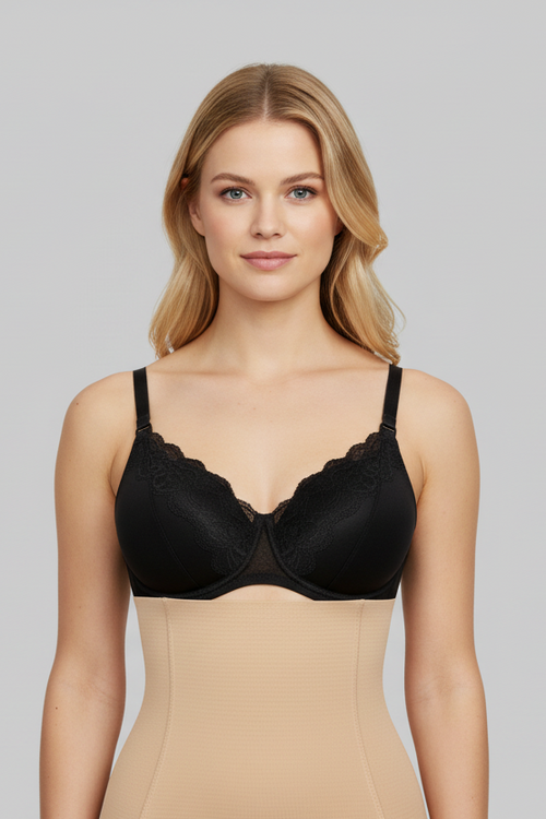 Woman wearing a black bra and beige shapewear against a gray background