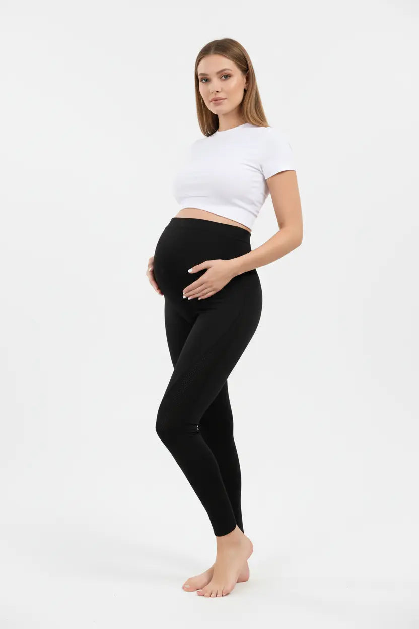 Woman wearing black leggings and a white crop top on a white background