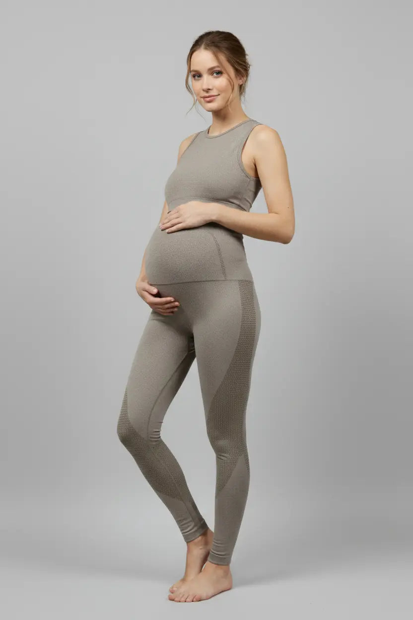 Woman wearing a gray tank top and leggings on a gray background
