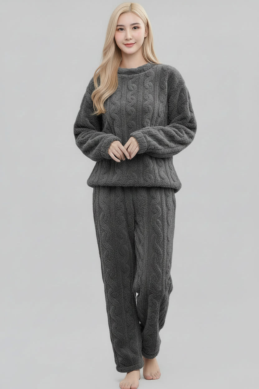 Woman wearing a gray cable knit pajama set on a plain background