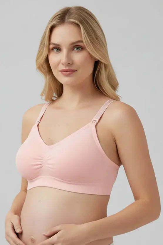 Pregnant woman wearing a pink maternity bra against a gray background