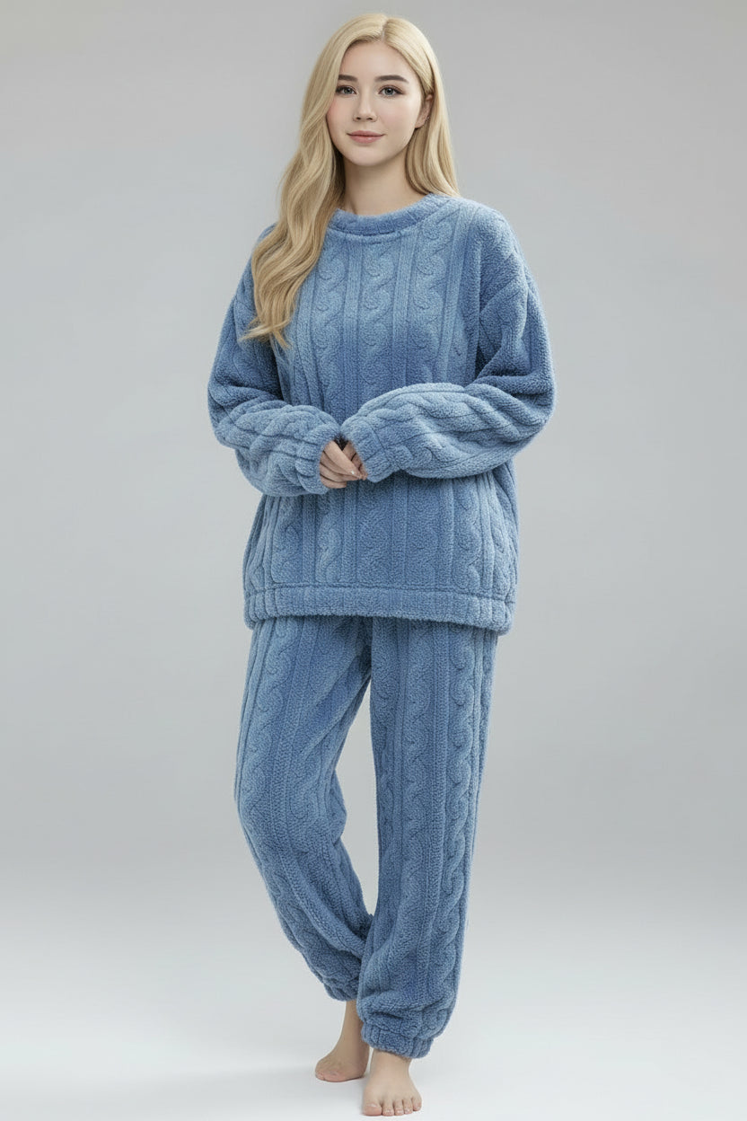 Woman wearing a blue cable knit sweater and pants on a gray background