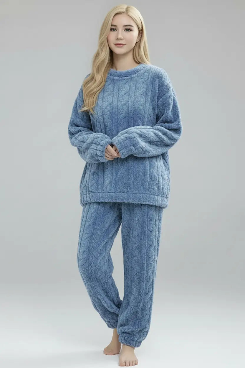Woman wearing a blue cable knit pajama set on a plain background